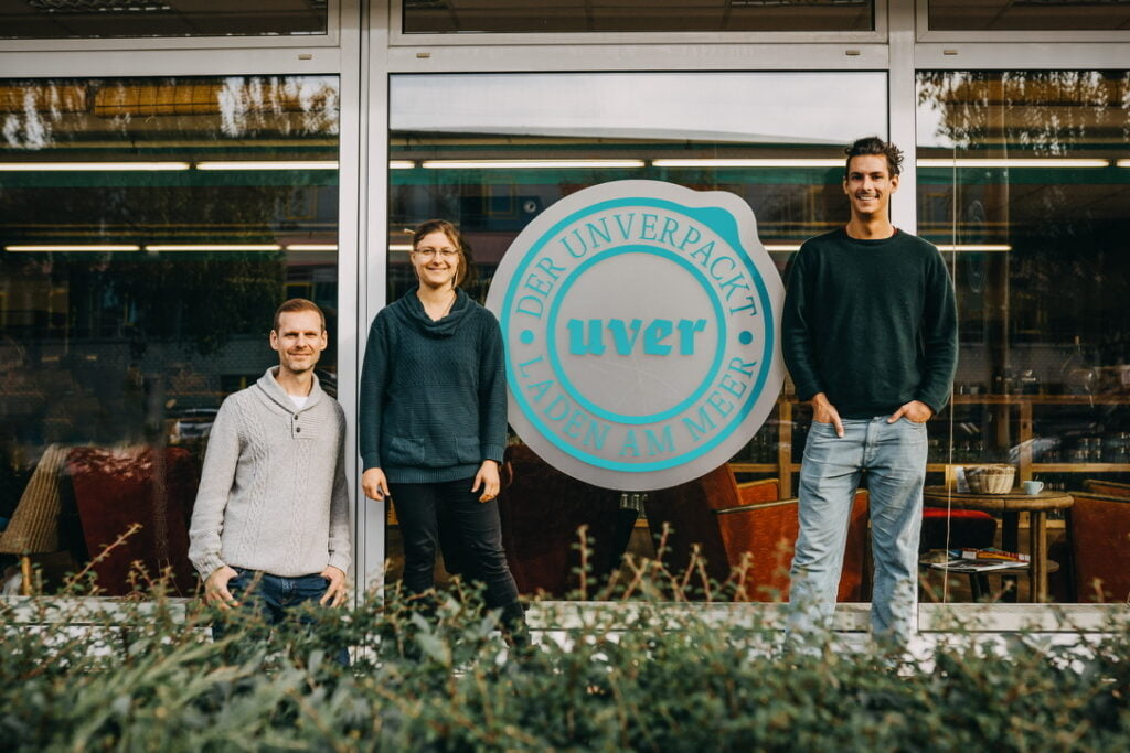 Die Gründer von UVER vor ihrem Unverpackt-Laden in Greifswald, umgeben von umweltfreundlichen Mehrwegbehältern.